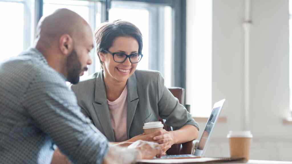 Two sales team members looking at their laptop while discussing Einstein Call Coaching