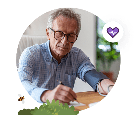Person writing at desk wearing a blood pressure cuff.